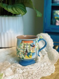 a coffee cup sitting on top of a doily next to a potted plant