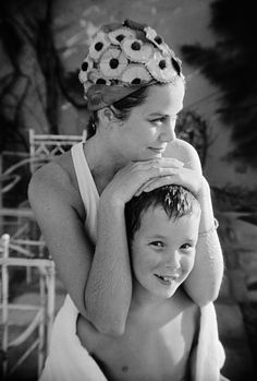 black and white photograph of a woman holding a young boy in her arms while they both have their heads wrapped around each other