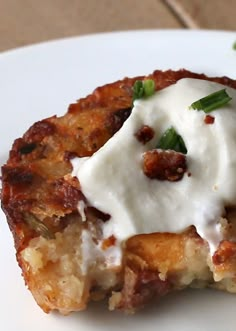 a close up of a piece of food on a plate with sour cream and chives