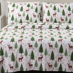 a bed with christmas trees and deers on the sheet set is shown in this image