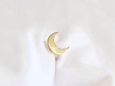 a gold crescent brooch sitting on top of a white cloth covered tablecloth with the moon in the middle