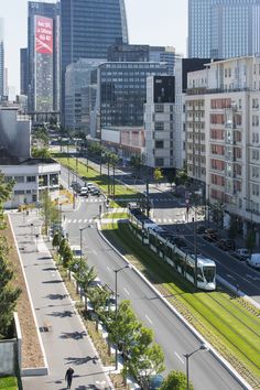 an aerial view of a city street with tall buildings and green grass in the foreground