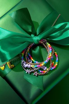 two bracelets tied together on top of a green gift box with a ribbon around it