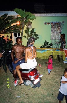 a man, woman and child sitting on a scooter in front of a party