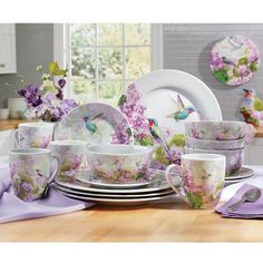 an image of a table setting with flowers and birds on the plate, cups and saucers