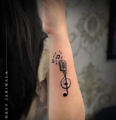 a woman's arm with musical notes and a microphone tattoo on her left wrist