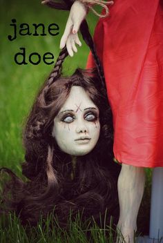 a creepy doll is being held by a woman's head with her hair in the grass