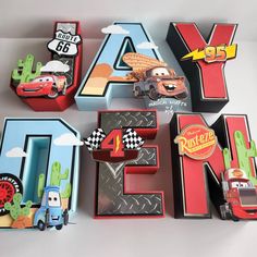 the letters are made out of cardboard and have cars on them, as well as magnets