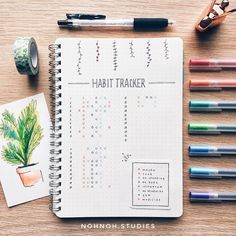 a notebook with the words habit tracker written on it next to markers and pencils