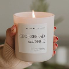 a woman holding a candle in her hand with the words gingerbread and spice on it