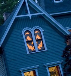 a house decorated for halloween with jack - o'- lanterns on the windows and pumpkin faces