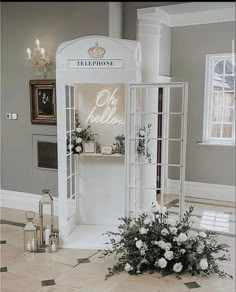 a white phone booth with flowers on the floor