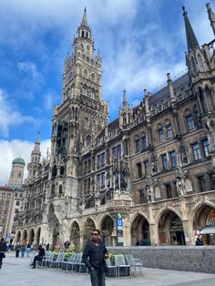 a man is standing in front of an old building with many windows and spires