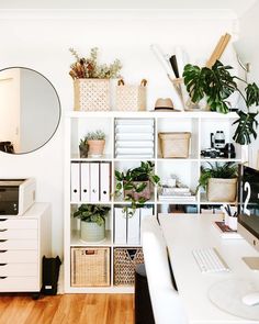 a white desk topped with lots of plants