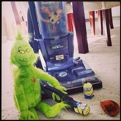 a green stuffed animal sitting on the floor next to a vacuum