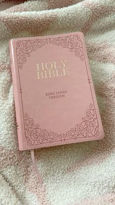 a pink bible laying on top of a blanket