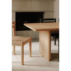 a wooden table and two chairs in front of a fireplace