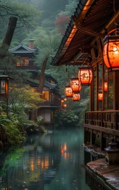 lanterns hanging from the side of a building over a body of water with trees in the background