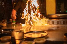 a man cooking food on top of a stove with flames coming out of the burner