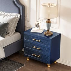 a blue nightstand with two drawers next to a bed and framed pictures on the wall