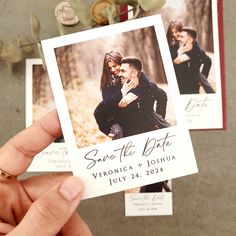 a person holding up a wedding save the date card