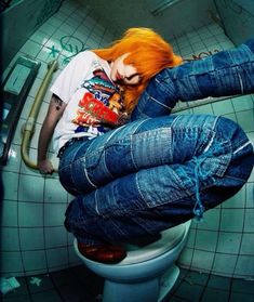 a woman with red hair sitting on top of a toilet