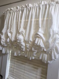 a white window curtain with ruffles hanging from it's side