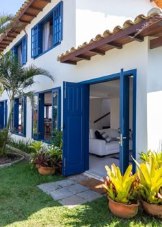 a white house with blue shutters and potted plants