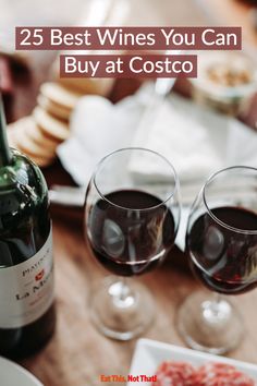 two wine glasses sitting on top of a wooden table next to a bottle of wine