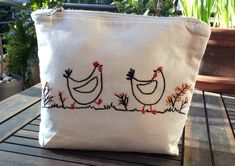 a white bag with two chickens on it sitting on a table next to potted plants