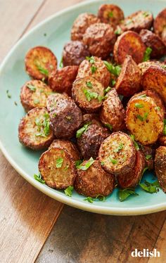 a blue plate topped with cooked potatoes on top of a wooden table