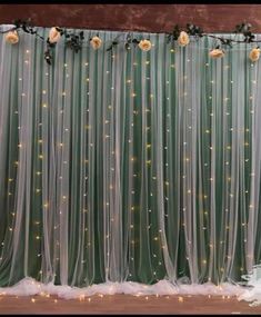 the wedding backdrop is decorated with flowers and lights in shades of green, white and gold