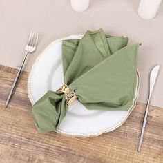 a place setting with green napkins and silverware