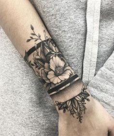 a woman's arm with flowers on it and a black stripe around the wrist