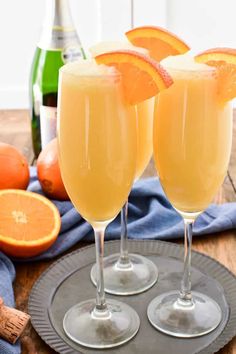 two champagne glasses filled with orange juice and garnished with an orange slice on the rim