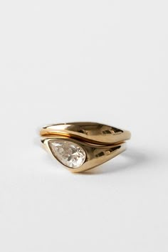 a gold ring with two pear shaped diamonds on the top, and an oval diamond in the middle