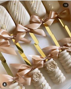 there are many white and gold desserts in the box with ribbons on them, as well as flowers