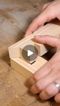 two hands are working on a wooden object