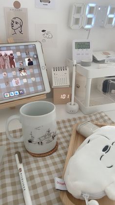 a table topped with a laptop computer next to a white cup and saucer on top of a wooden tray