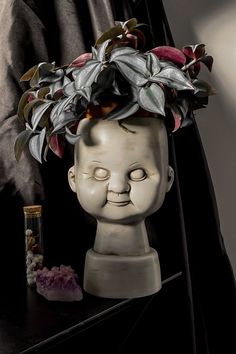 a ceramic head with flowers on it next to a bottle