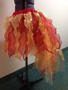 an orange and red dress on a mannequin's head stand in front of a white wall