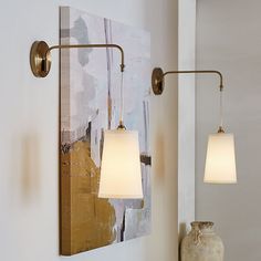 two lamps are hanging on the wall next to a vase