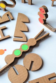 the letters are made out of cardboard and have different colored circles on them, along with small wooden pegs