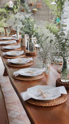 the table is set with white plates and vases filled with baby's breath flowers