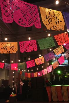 brightly colored paper doily hanging from the ceiling in an indoor event space with people looking on