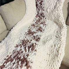 a white and brown blanket sitting on top of a couch