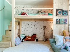 a room with bunk beds and stuffed animals on the floor, in front of a staircase