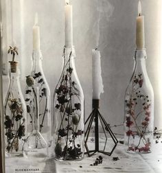 several bottles with flowers and candles in them