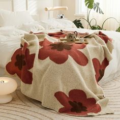 a bed with a blanket on top of it next to a candle and potted plant