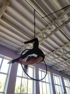 a woman is doing aerial tricks on a hoop